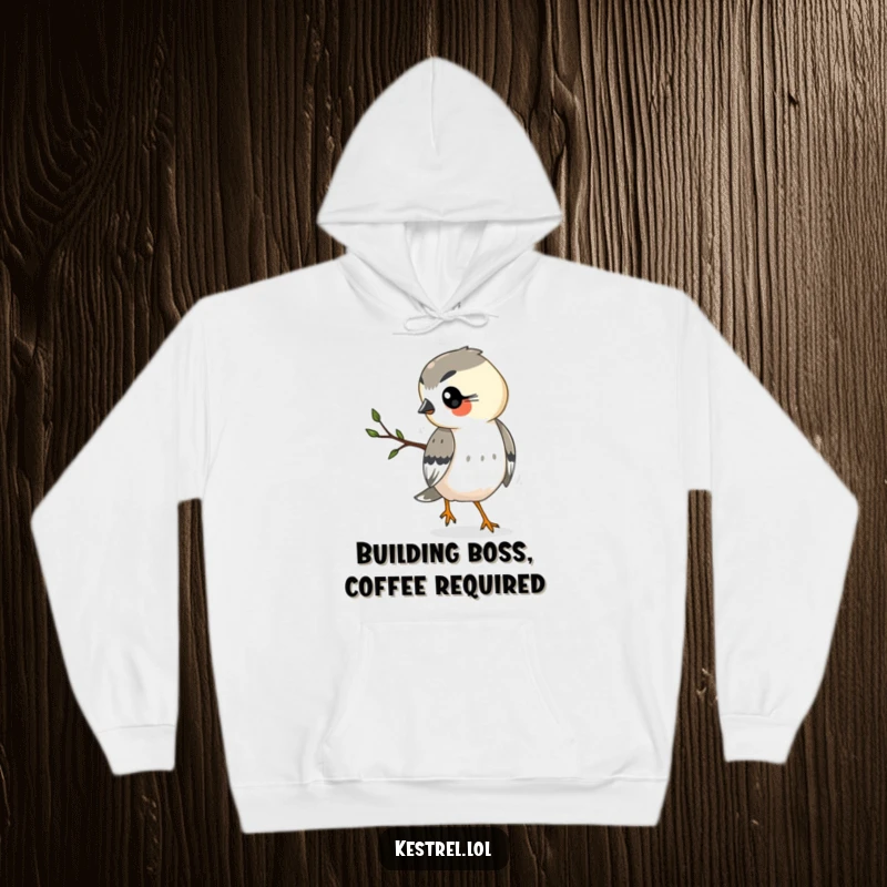 Funny kestrel hoodie depicting a hard-working kestrel carrying a small twig, perfect for chilly days and laughs.