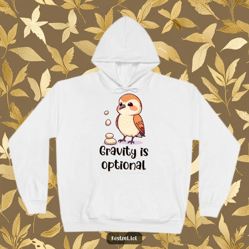 Funny Kestrel Juggler Hoodie: A kestrel character comically attempts to juggle pebbles, offering warmth and whimsical entertainment. Perfect for lounging.