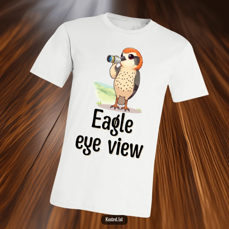 Funny kestrel t-shirt depicting a curious bird with tiny binoculars scanning a landscape. Humorous explorer wear.