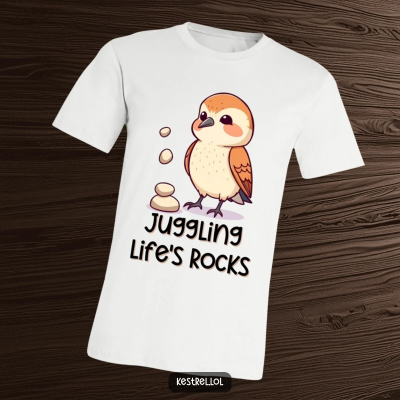 Funny Kestrel Juggler T-Shirt: A kestrel comically attempts to juggle three small pebbles, proving practice makes imperfect. Funny and relatable apparel.