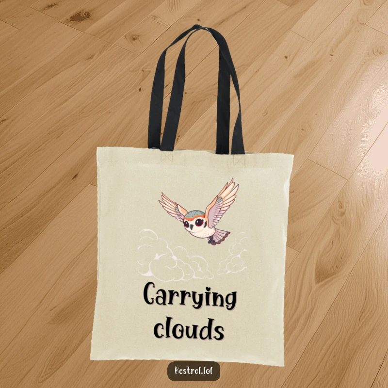Funny tiny kestrel tote bag depicting a cute bird with exaggerated eyes gracefully diving through fluffy clouds, perfect for carrying items with playful charm.