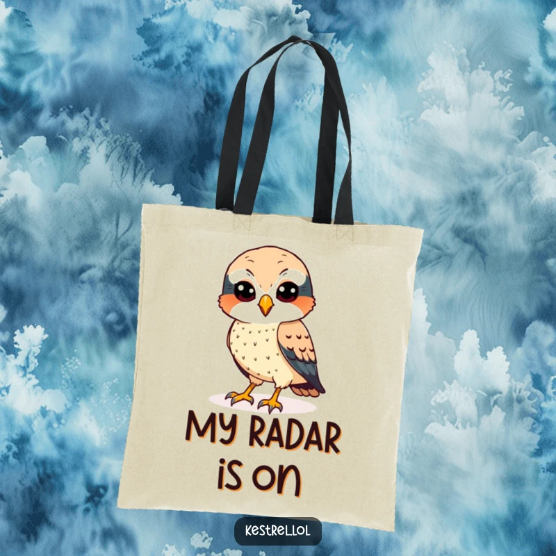 Funny kestrel tote bag with a cheerful bird featuring sharp eyes, scanning the ground.